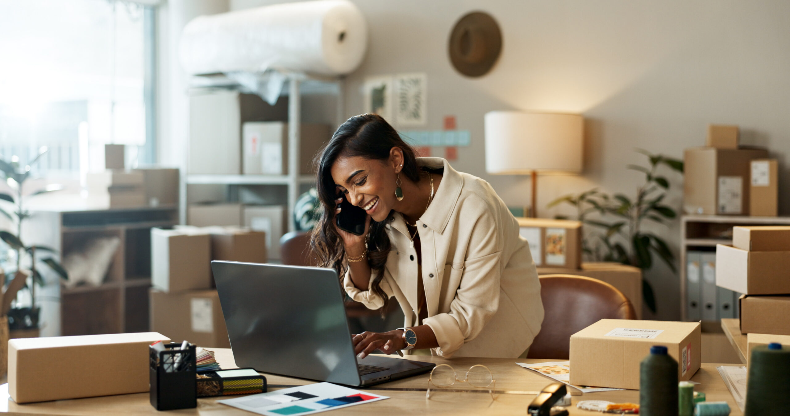 Phone call, small business happy woman with laptop for communication in office.